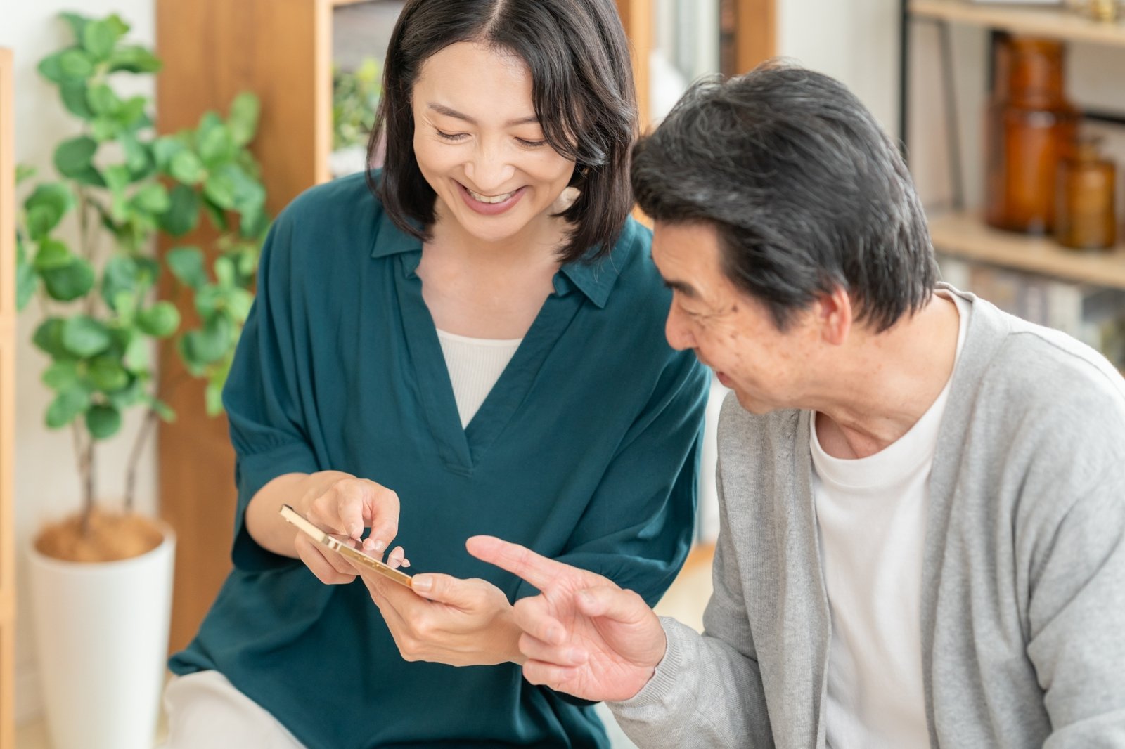ミドル世代の夫婦がリビングで一緒にスマホを眺めている様子